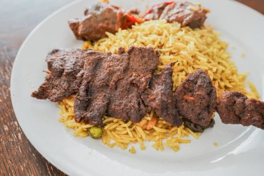 Nijerya Baharatlı Suya sebze pilavıyla servis edilir.