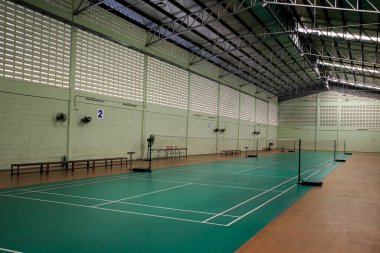 Yeşil ve beyaz tenis kortu, ağlı ve birkaç banklı. Mahkeme boş.