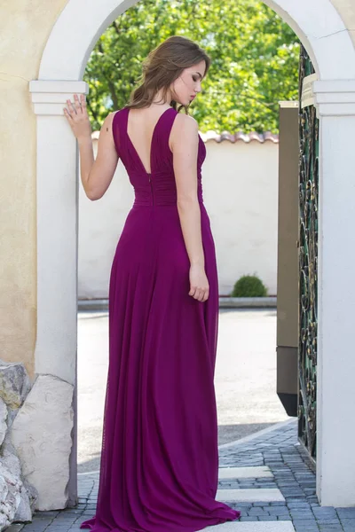身穿紫色长裙的妇女背对着墙站在门口 图库照片
