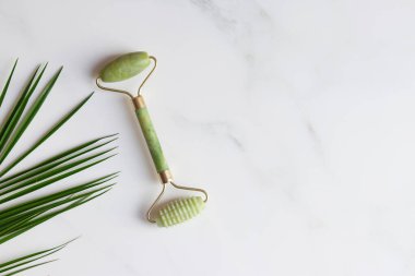 Yeşim yüzlü masajcı mermer masada fotokopi alanı ile birlikte. Geleneksel Çin yüz masajı için özel cihazlar, Gua Sha. Güzellik ve sağlık hizmeti konsepti. Üst manzara, düz uzanma.