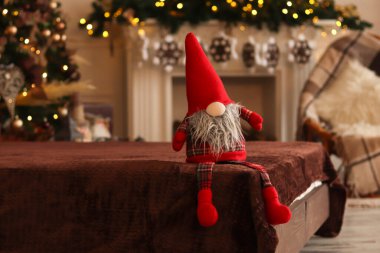 Süslü Noel odasının arka planında komik bir cüce oturuyor. Seçici odak, boşluğu kopyala.