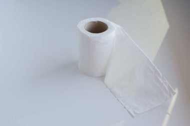 Masanın üzerindeki beyaz rulo tuvalet kağıdı güneş ışığıyla aydınlatılmış..
