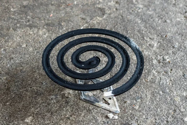 Burning black mosquito repellent coil on concrete floor background.