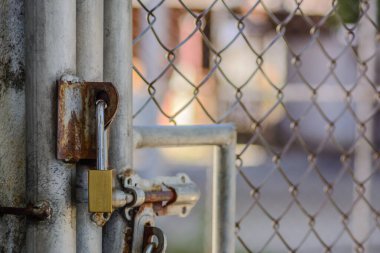 Çelik ızgara kapısını doğal ışık arka planına kilitlemek için pirinç anahtar.