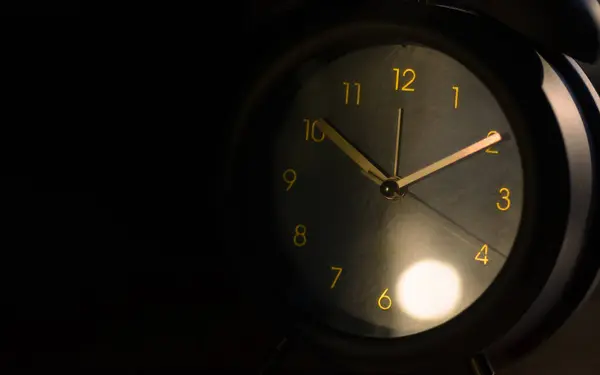 Close up of alarm clock face in dark background.