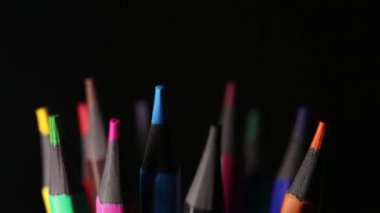 Siyah arkaplan üzerinde dönen renkli kalemler, okul için kırtasiye malzemesi