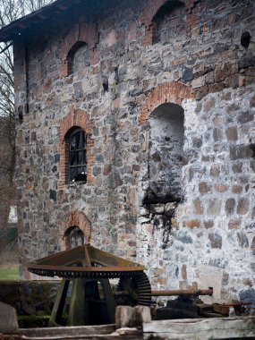 Hızlı bir nehrin akışı değirmen tekerine aktı. Su çarkı ve ormanlardaki eski değirmen. Hızlı su üzerindeki bir değirmenin parçası. Taş, antik yapı..