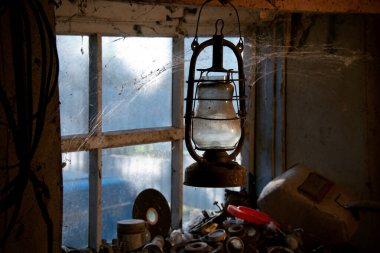 Köydeki garaj. Kırsal ortam. Yarasa lambası. Kaynakçının envanteri. Işık parıltıları garaj aletlerini aydınlatıyor. Antika gaz lambası..