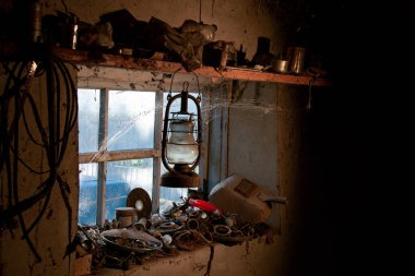 Köydeki garaj. Kırsal ortam. Yarasa lambası. Kaynakçının envanteri. Işık parıltıları garaj aletlerini aydınlatıyor. Antika gaz lambası..