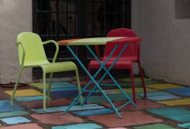 Balboa, San Diego 'daki İspanyol köyünde yeşil ve kırmızı metal sandalyeler ve masa