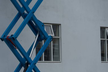 Reykjavik, İzlanda 'daki bir binanın beyaz boyalı duvarının yanında mavi asansör yükseltilmiş.