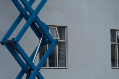 Reykjavik, İzlanda 'daki bir binanın beyaz boyalı duvarının yanında mavi asansör yükseltilmiş.