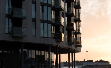 Glowing sunset highlights on glass walls of condo in Tjuvholmen, Oslo, Norway clipart