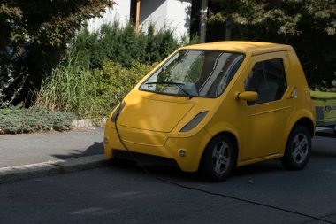 Norveç, Oslo, Rodelokka 'da sessiz bir sokağa park etmek için park edilmiş şirin sarı elektrikli araba.