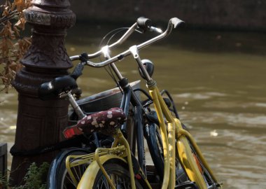 Renkli koltuk kılıfları ve parlak kol parmaklıkları Amsterdam 'da bir sokak lambasına zincirlenmiş bisikletler.