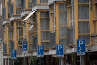 Row of disability parling signs under yellow building with white nook windows, Lastage, Amsterdam clipart