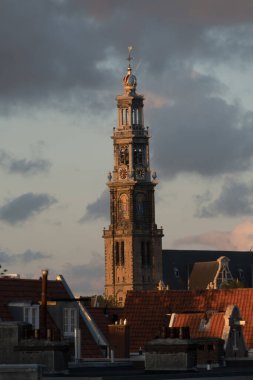 Looking from a window of a condo at glowing scarlet colors highlighting the  spear of Westerkerk, Amsterdam clipart