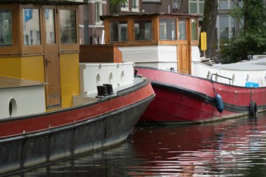 Sessiz güneşli bir öğleden sonra ve renkli tekneler ve onların yansımaları Brouwersgracht, Amsterdam 'da