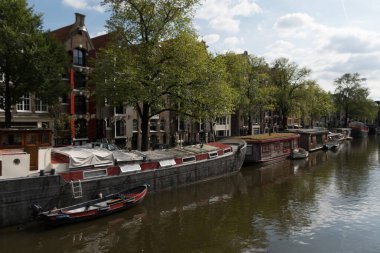 Sessiz güneşli bir öğleden sonra ve renkli tekneler ve onların yansımaları Prinsengracht, Jordaan, Amsterdam 'da