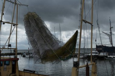 Hollanda, Volendam marinasındaki balıkçı teknesinin üzerinde asılı dev bir balık ağı.