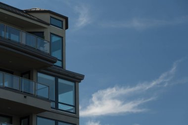 Top floor of new contemporary condo building on Alki with bright blue sky in the background clipart