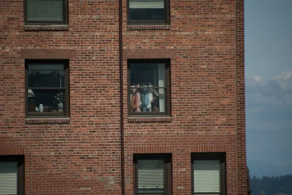 Port Townsend feribot terminali yakınlarındaki Viktorya döneminden kalma kırmızı tuğla bir binanın uzun penceresinde asılı giysiler.