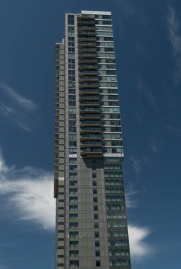 Bellevue iş bölgesinde tek başına duran cam ve çelik kule arka planda canlı yaz gökyüzü bulunan beyaz bulutlarla çakışıyor.