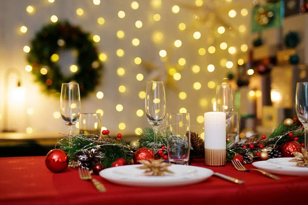 stock image Red table served for family festive dinner. Living room decorated with lights