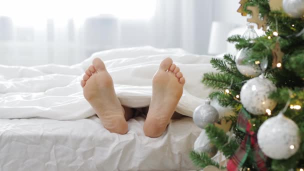 放松和快乐的概念 在装饰过的圣诞树附近擦伤女性腿 — 图库视频影像