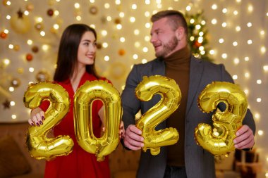 Mutlu erkek ve dişi elinde 2023 balon tutuyor.