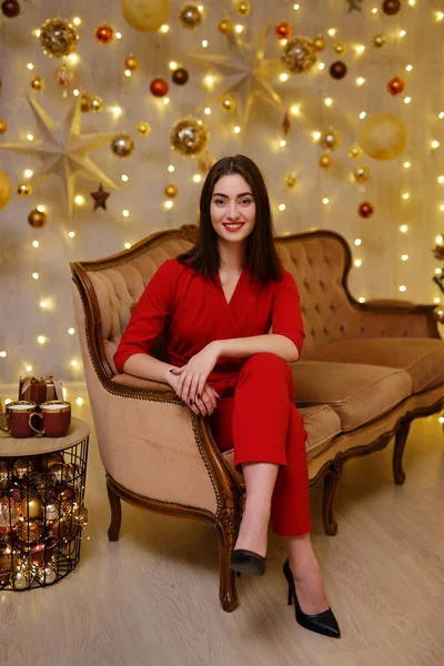 笑顔可愛いです女性で赤いスーツでソファに座ってクリスマス飾り — ストック写真
