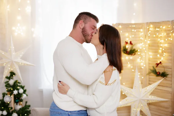美丽的夫妻在装饰过的圣诞房间接吻 — 图库照片