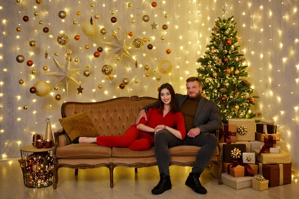 男と女座っていますソファにクリスマス装飾された部屋でLedライト — ストック写真