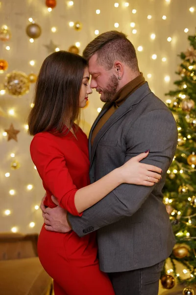 かわいいカップルでお祝いの服抱擁でクリスマス装飾された部屋 — ストック写真