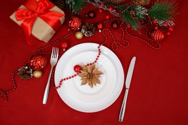 Köknar dallı beyaz seramik tabak, hediye ve kırmızı Noel süslemeleri.