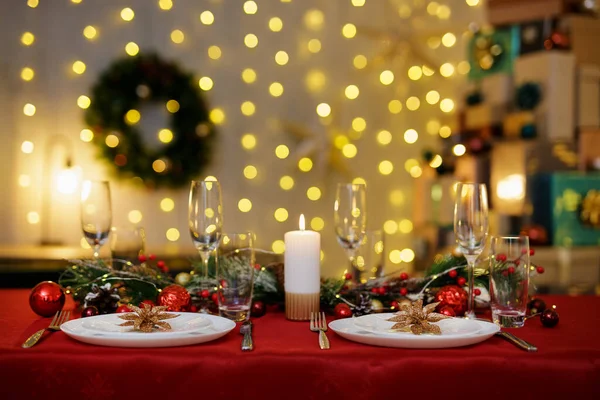 크리스마스 저녁에는 접시와 샴페인 잔으로 장식된 아름다운 탁자가 배경의 갈런드 — 스톡 사진