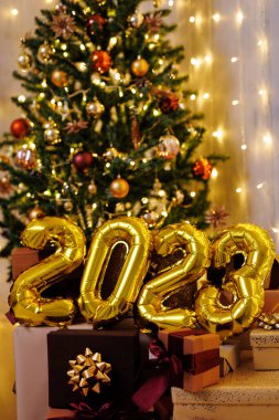 Mutlu yıllar. Altın 2023 hava balonu numaralarına ve Noel ağacının yanındaki hediye kutularına yakın durun.