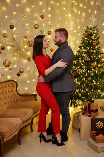 かわいいカップルでクリスマスツリーの近くに抱きつくお祝い服 — ストック写真