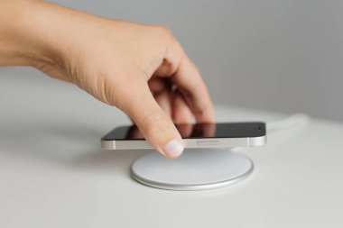Hand putting mobile phone on wireless battery charger