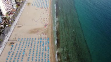 Yaz tatili ve seyahat konsepti - Benidorm, İspanya 'da yaz gezisinin güzel hava manzarası, turistlerle dolu plaj, güneşlik yataklar ve şemsiyeler