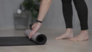close up of woman preparing a yoga mat for training on the floor at home 