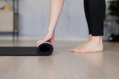 Siyah yoga minderini evdeki zeminde eğitime hazırlayan kadına yakın durun.