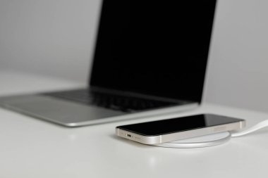 Ön planda kablosuz şarj aleti ve arka planda dizüstü bilgisayar.