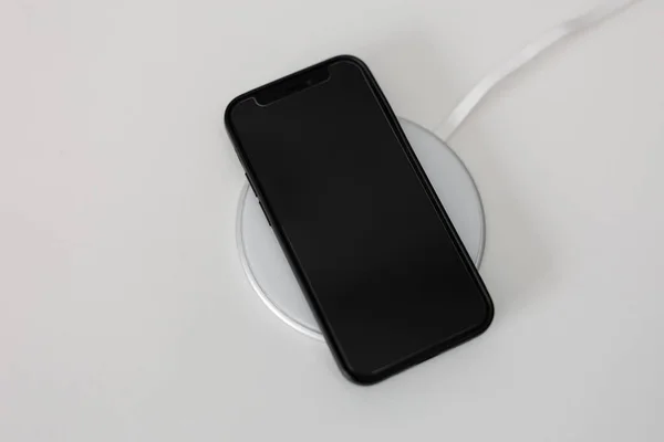 Czarny Nowoczesny Telefon Leżący Białej Ładowarce Bezprzewodowej — Zdjęcie stockowe