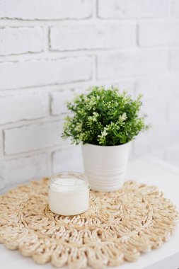 Beyaz mumlar tezgahta saksıda, masa paspasında da fotokopi alanı var.