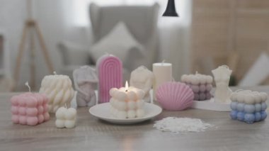 Oturma odasındaki masanın üstünde renkli el yapımı mumlar var. Kadın eli özel bir şapkayla alevi söndürüyor.