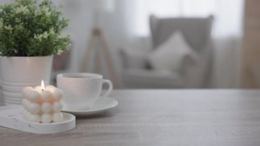 Sabah arkaplanı - bir fincan kahve, bitki ve yanan mum evdeki masada.