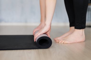 Yoga ve meditasyon konsepti - Çıplak ayaklı kadının evde eğitim için yoga minderi hazırlaması