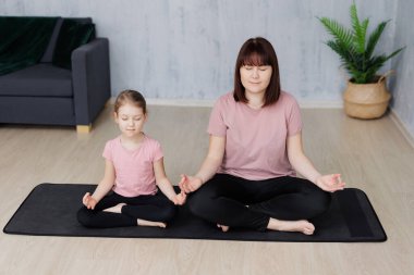 aile ve spor konsepti - birlikte yoga yapan küçük anne ve kızın portresi, lotus poz evde oturan