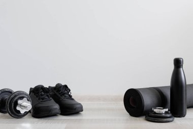 Dambıl, spor ayakkabısı ve su şişesiyle ahşap zemin üzerinde fotokopi alanı olan spor teması